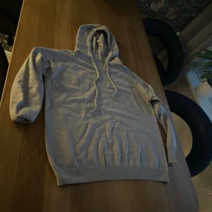 Ljusgrå hoodie med snörning - En stilren ljusgrå hoodie med huva och snörning. Tröjan har långa ärmar och ribbade muddar vid ärmslut och nederkant. Perfekt för chill dagar och enkel att matcha med jeans eller joggers.