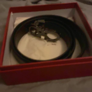 Svart skärp med metallspänne - Snyggt svart bälte med ett stilrent metallspänne, levereras i en röd ask. Perfekt accessoar för att lyfta din outfit med en klassisk och tidlös look. Passar till både jeans och kostymbyxor.