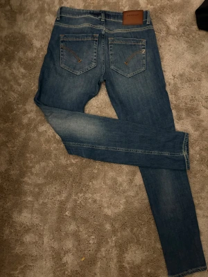 Blå skinny jeans Dondup Monroe W26 - Säljer ett par blå skinny jeans från Dondup, modell Monroe. Klassisk femficksdesign med snygga kontrastsömmar och läderpatch bak i midjan. Jeansen har en smal passform och är tillverkade i mjukt denimtyg. Perfekta till sneakers eller boots.