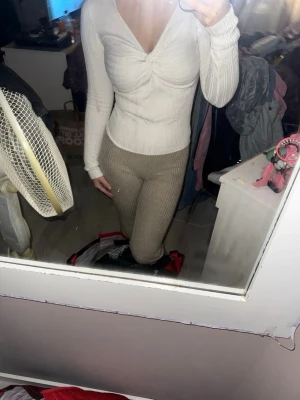 Vit ribbad långärmad topp med twist - Säljer en vit ribbad topp med lång ärm och snygg twist-detalj framtill. Toppen har v-ringad hals och är figurnära i passformen. Materialet känns mjukt och stretchigt, perfekt att styla med jeans eller kjol. Passar dig som gillar stilrena och trendiga plagg.