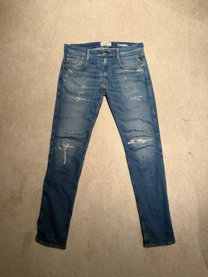 Replay Anbass slim fit jeans blå - Säljer ett par Replay Anbass slim fit jeans i klassisk blå tvätt med slitna detaljer. Perfekt passform med smal siluett och stretchigt jeanstyg. Hör av er vid intresse! (Pris går att diskuteras)🤝
