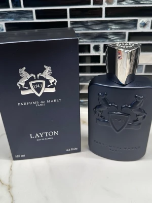 Layton Eau de Parfum 125ml - Lyxig parfym från Parfums de Marly, Layton, 125 ml. Tillverkad i Frankrike. Ingredienser: alkohol denat, aqua (vatten), limonene, linalool, citral, geraniol. Snygg design som sticker ut och passar dig som vill ha något exklusivt.