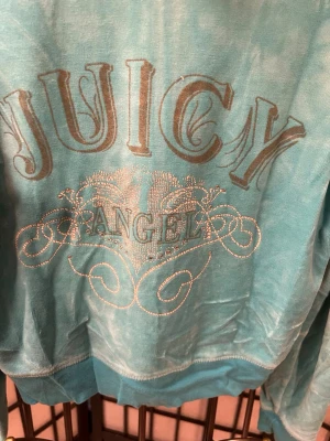 🌟 Juicy Couture “Juicy Angel” Hoodie – Baby Blue Y2K Classic 🌟 - Äkta Juicy Couture hoodie i mjuk babyblå med ikoniska “Juicy Angel”-trycket – ett äkta Y2K-plagg från tidigt–mitt 2000-tal 💖 Perfekt för samlare, Y2K-fashionälskare eller vem som helst som vill ha den där mysiga glam-viben à la Paris Hilton.  Storlek: [Din storlek] Färg: Babyblå Material: Velour (mjukt, fluffigt, stretchigt) Skick: [t.ex. mycket bra vintage-skick – små tecken på användning]  💎 Sällsynt Y2K-hoodie – hög samlarpotential 💎 Perfekt för lager-på-lager eller som statement-plagg 💎 Slut