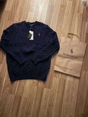 Mörkblå stickad Ralph Lauren tröja - Säljer en ny oanvänd sticka ralph lauren tröja som är väldigt fin! Den kommer även i påsen😊. Skriv gärna om ni har några fler funderingar