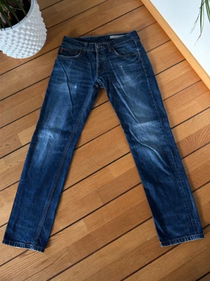 Blå tapered jeans från Big Star - Säljer ett par klassiska blå jeans från Big Star med regular fit och tapered ben. Jeansen har fem fickor, snygga slitningar och kontrastsömmar. Tillverkade i slitstarkt bomullsmaterial och passar perfekt till en avslappnad stil.
