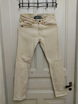 Tiger of Sweden vita jeansbyxor - Snygga vita jeansbyxor från Tiger of Sweden, modell Rex. Klassisk femficksdesign med raka ben och normal passform. Tillverkade i bomull med skinnpatch bak i midjan. Perfekta för dig som gillar stilrena och ljusa jeans.