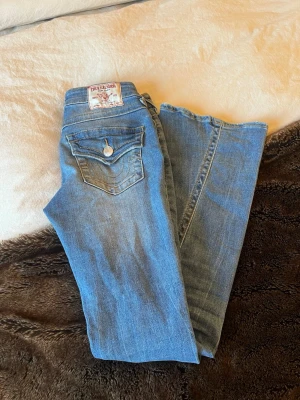 True Religion Joey Low Rise Flare Jeans - Säljer ett par blå jeans från True Religion, modell Joey Low Rise Flare. De har låg midja och utsvängda ben, storlek 23 varsamt använda och inget sönder tramp 