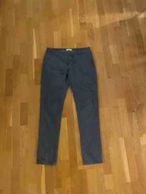 Dondup chinos i 100% bomull, storlek 33 - Snygga blå chinos i rak modell med normal passform. Byxorna är tillverkade i 100% bomull och har klassiska fickor fram och bak. Perfekta för dig som gillar stilrena och bekväma byxor. Färgtonen är mörkblå och materialet känns mjukt mot huden. Väldigt fint skick. Säljer då mina ben blivit för stora för dom. Bra i längden för mig på 183. 