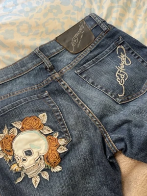 Ed Hardy jeans - Säljer ett par mörkblå lågmidjade jeans från Ed Hardy med broderat logotyp på fickorna. De är nästan helt oanvända 