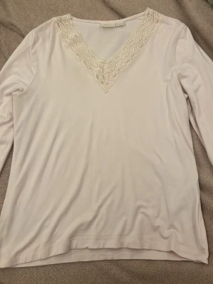 Ljus rosa långärmad tröja med spets Gina Tricot - Säljer en ljus rosa  långärmad tröja från Gina Tricot i storlek 170. Toppen har en snygg v-ringning med dekorativ spetsdetalj i halsen. Materialet är mjukt och lätt, perfekt för dig som gillar en enkel men söt stil. Använt 1 gång 