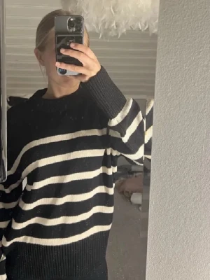 Svartvit randig stickad tröja Gina Tricot - Säljer en svart stickad tröja från Gina Tricot med vita horisontella ränder. Tröjan har rund hals, långa ärmar och ribbade muddar vid hals, ärmslut och nederkant. Perfekt för dig som gillar enkel och stilren design.