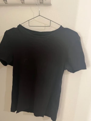 Svart basic t-shirt  - Jag säljer en basic t-shirt som är i storlek M, tröjan är ribbad, och kort. 