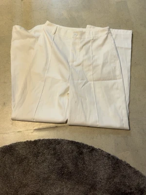 Vita kostymbyxor från SHEIN, storlek S - Snygga vita kostymbyxor från SHEIN i storlek S. Byxorna har klassisk rak passform med pressveck och bälteshällor. Tillverkade i ett mjukt och lätt material som ger en clean och fräsch look. Perfekta för dig som gillar stilrena outfits.