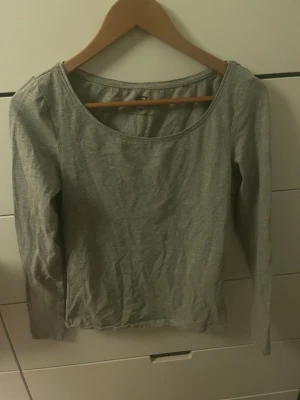 Grå långärmad topp från lager 157 - En enkel och stilren grå långärmad topp från lager 157 med rund halsringning. Tillverkad i mjuk bomull som känns skön mot huden. Perfekt att matcha med jeans eller kjol för en avslappnad look.