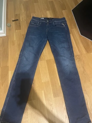 Replay Anbass Hyperflex jeans blå - Säljer ett par Replay Anbass Hyperflex jeans i mörkblå tvätt. Slim fit-modell med klassiska fem fickor, snygga kontrastsömmar och stretchigt material för extra komfort. Märkespatch bak i midjan och diskret Replay-detalj på fickan. Perfekta jeans för dig som gillar stilren look. Använda 1-2 gånger så inga defekter på jeansen nästan som nya