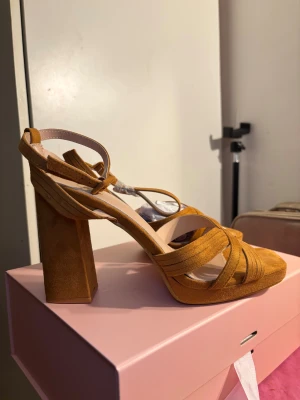 klackskor / blocklackar– stl 41 (som nya) - Eleganta klackskor i mocka-look med stabil blockklack och justerbar ankelrem. Perfekta till fest, middag eller event. Endast provade inomhus.  • Storlek: 41 • Märke: ERYNN • Skick: Nya / aldrig använda • Färg: Mocka orange /brun