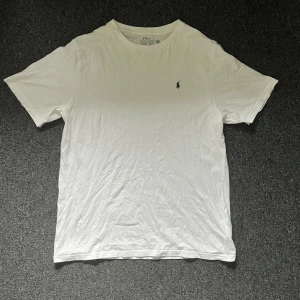 Vit Polo Ralph Lauren T shirt - Klassisk vit t-shirt från Polo Ralph Lauren med rund hals och liten broderad logga på bröstet. Tillverkad i mjuk bomull och har en normal passform. Är storlek XL barn men sitter som S/M i vuxen storlek. Är i nytt skick i den är annvänd 1-2 gånger. Hör av dig vid frågor eller funderingar!