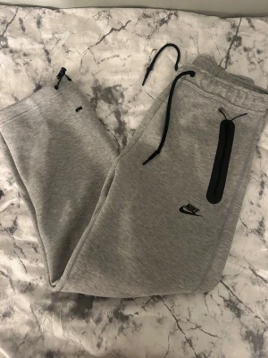 Grå nike tech byxor  från Nike  - Gråa nike tech byxor, endast användt ett fåtal gånger. Nya nike tech modellen 