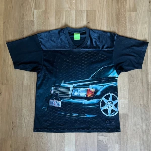Svart HUF t-shirt med biltryck - Säljer en svart t-shirt från HUF i mesh-polyester med ett stort tryck av en bil på framsidan. T-shirten har v-ringad krage och korta ärmar. Märkeslapp sitter nere vid fållen. Perfekt för dig som gillar streetwear och coola motiv. Längd: 66cm Bredd: 48cm Arm: 20cm Köptes för 1099kr. Använt den väldigt få gånger.Pris kan diskuteras.