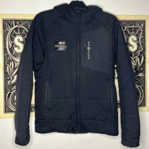 Sail Racing jacka svart - Svart Sail Racing jacka i mycket bra skick men har fläck i vänstra armen och lite på luvan, pm vid intresse.