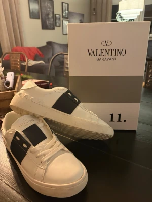 Valentino Garavani strl 42 (nästintill ny skick)  - Säljer ett par snygga Valentino Garavani sneakers i vitt skinn med bred marinblå detalj över sidan och snörning.  dessa feta valention skor i en fett navy färg extremt bra skick strl 42 bag och box fås med  🤩 säljer för 1999 men vid smidig affär så kan jag sälja billigare         Hör  av er vid frågor eller annat   #valention