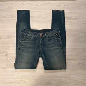 Blå Replay Luz jeans, midja 28/32 - Snygga blå jeans från Replay, modell Luz. Klassisk femficksdesign med guldfärgad knapp och Replay-logga på fickan. Jeansen har en lätt tvättad look och raka ben. Perfekta för dig som gillar en tidlös stil med modern touch.