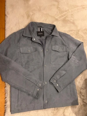 Grå mocka overshirt  - Riktigt schyst mocka overshirt från dressmann. Size M passar 184, 67kg. Nypris 1000. Cond 9/10 använd fåtal gånger men syns ej.  Tveka inte att skriva om ni har frågor!