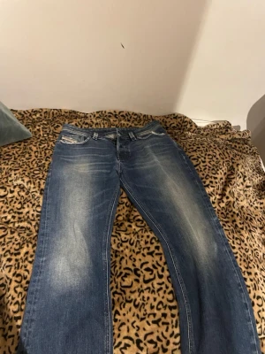 Blå jeans från Diesel Industry - Säljer ett par klassiska dark blue wached jeans från Diesel med snyggt slitna detaljer på fickorna. Jeansen har raka ben och normal passform. Passar tillsammans med allt nästan. Storleken är w29 och L32, 1500+kr ny pris.