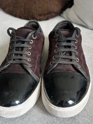 Lanvins - Snygga sneakers från Lanvin i vinröd mocka med eleganta detaljer. Skorna kombinerar en stilren design med en unik touch, vilket gör att de passar till både vardag och mer uppklädda tillfällen.  