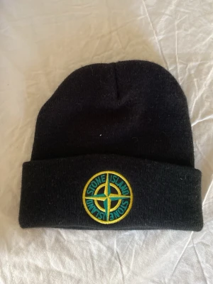 Svart Stone Island mössa - Svart mössa från Stone Island i mycket bra skick. Använd fåtal gånger!