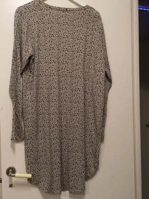 Beige leopardmönstrad klänning XL - Säljer en beige långärmad klänning från mywear i storlek XL. Klänningen har ett leopardmönster i svart och är tillverkad av mjuk viskos med lite stretch från elastan. Rund halsringning och rak passform, perfekt för dig som gillar djurmönstrat.