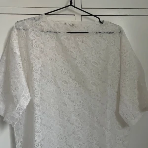 Vit spetsblus med blommönster - Säljer en vit blus i spets med blommigt mönster. Blusen har en lös passform och trekvartsärmar, perfekt för vår och sommar. Materialet är mjukt och luftigt, vilket gör den skön att bära. Passar dig som gillar romantisk och feminin stil.❤️