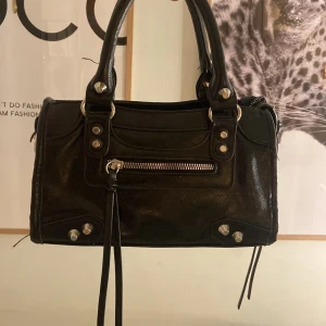 Svart handväska  - Säljer en svart handväska med klassiska silverfärgade nitar och detaljer. 