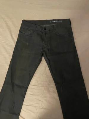 Svarta jeans från J.Lindeberg - Svarta jeans från J.Lindeberg med klassisk femficksdesign och rak passform. Jeansen har en enkel look utan synliga detaljer och är tillverkade i ett mjukt bomullsmaterial med lite stretch. Perfekta för dig som gillar stilrena och mörka jeans.