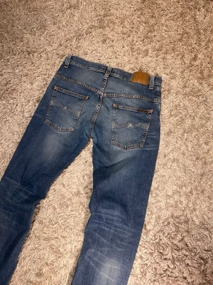 Nudie jeans thinn finn slim fit herr w32  - Nudie jeans modell thinn finn. Slim fit med en fet fade och snygga honecombs. Mycket bra skick, inga märkvärdiga defekter. Storlek w32 L32. Postas samma dag slm köp eller dagen därpå🙌💯