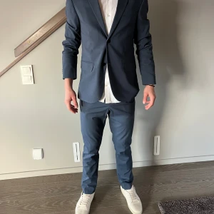 Blå kostym med kavaj och byxa - Säljer en stilren blå kostym med matchande kavaj och byxa som är använd 1 gång. Kavajen har klassisk passform, två knappar framtill och fickor med lock. Byxorna är raka och sitter snyggt. Materialet känns som polyester eller ullblandning. Nyårsoutfiten är räddad! Skorna hittar ni i min profil (Obs skjortan medföljer inte) Jag är 183cm lång och väger 72kg