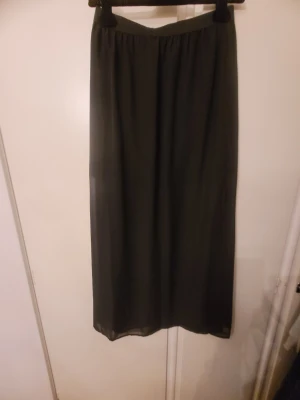 Svart långkjol från Divided H&M - Säljer en svart långkjol från Divided H&M i storlek 40. Kjolen har en enkel och flowy design med resår i midjan för skön passform. Perfekt att styla med sneakers eller boots. Materialet känns lätt och luftigt.