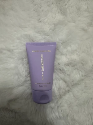 Lila balm från Sam McKnight 30ml - Säljer en lila tub med Happy Endings Nourishing Balm från Sam McKnight. Tuben rymmer 30 ml och har guldfärgad text. Perfekt att ha i väskan för snabb touch up. Tuben är gjord i plast och har en smidig klickkork.