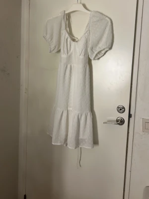 Vit långklänning med puffärmar - Superfin vit långklänning med puffiga kortärmar och snygg snörning i ryggen. Klänningen har ett diskret prickigt mönster och volang nedtill som ger en romantisk vibe. Materialet känns lätt och luftigt, perfekt för varma dagar. Pris kan diskuteras, tvätt ingår innan leverans ❤️