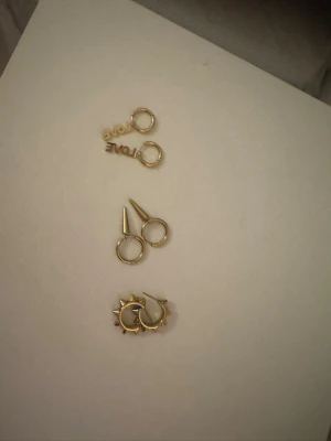 Edblad - Bilden visar tre par örhängen i guld, varav ett par har texten 'LOVE', ett par har är peak med spets detaljer och ett par är peak. De med pigar på sig saknar pluppar tyvärr. Tänker mig 399kr  för alla nypris ca 349-399kr per styck. Har alldrig använt Love örhängena. Alla smycken är från Edblad 