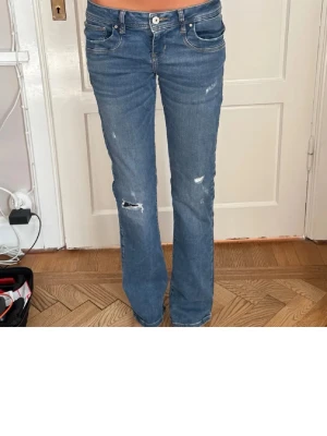 Ltb  blå bootcut jeans - Säljer ett par ltb jeans i blå tvätt med bootcut-snitt och låg midja. Jeansen har slitna detaljer och hål på benen för en cool, avslappnad vibe. 