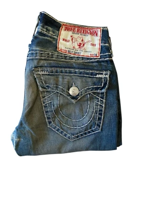 True Religion Jeans Billy Super T - True Religion Jeans, Billy Super T, storlek 31, nice rare wash, bra skick men knä reperation finns, midja 41cm, längd 104cm, innerben 75cm och ben öppning 21.5. Skriv om ni undrar någonting 📲
