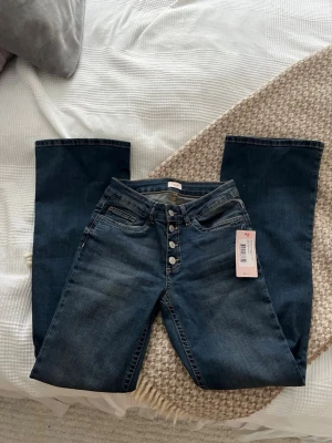 Midwaist jeans från Nelly - Helt oanvända utsvängda jeans från Nelly i mörkblå färg, tyvärr för korta på mig