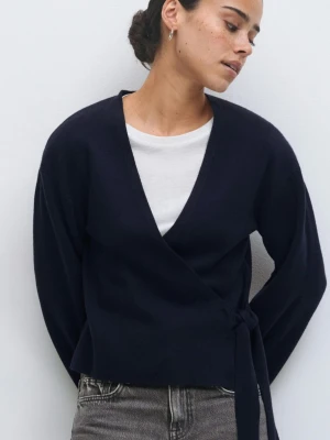 Mörkblå omlottkofta från Gina Tricot - Snygg mörkblå omlottkofta från Gina Tricot med knyt i midjan och långa, lite vidare ärmar. Koftan har en djup v-ringning och är gjord i mjukt stickat material. Perfekt att slänga på sig över en t-shirt eller linne. Storlek S. 50% viskos. Ny med prislapp.