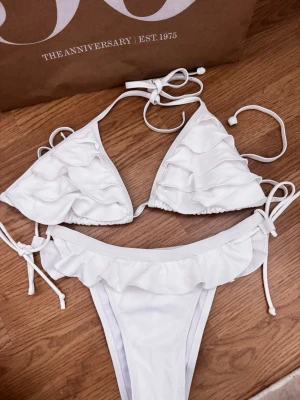 Vit bikini med volanger - Vit bikini med volangdetaljer och knytband. Använd en gång men tyvärr för stor på mig