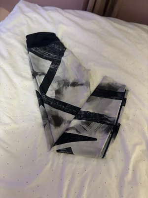 Svarta och vita leggings med mönster - Säljer ett par leggings med svartvitt abstrakt mönster. De har hög midja och är tillverkade i ett stretchigt syntetmaterial som sitter tight mot kroppen. Perfekta för dig som vill ha något bekvämt och snyggt till träning eller chill.