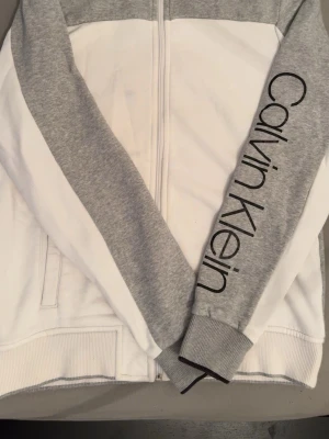 Calvin Klein hoddie  - Vitt grå Calvin Klein hoddie,står Calvin Klein på ena armen,mkt bra skick 