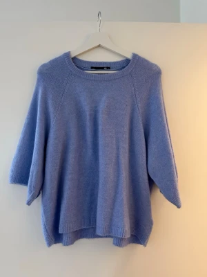 Ljus blå stickad tröja 157 S - Mysig ljus blå stickad tröja från 157 i storlek S. Tröjan har en avslappnad passform, rund halsringning och trekvartsärmar. Perfekt för lager på lager under kyliga dagar. Enkel och stilren design som är lätt att matcha.