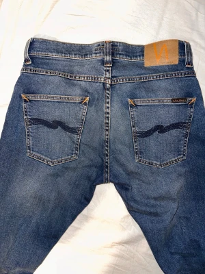 Sprillans nya Nudie Jeans - Grim Tim  30/30 - Säljer ett par helt nya blå jeans från Nudie  i storlek 30/30. Aldrig använda!!! Endast provad på dem. Köpta på NK i Göteborg för 1600kr. Kvitto finns. Skriv vid minsta funderingar. 