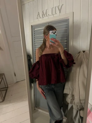 Vinröd offshoulder blus Garçonne - Säljer en vinröd offshoulder blus från Garçonne i storlek S/M. Blusen har vida puffärmar och är croppad med en luftig passform. Perfekt för dig som vill sticka ut med en trendig och elegant topp. Materialet känns lätt och skönt mot huden.